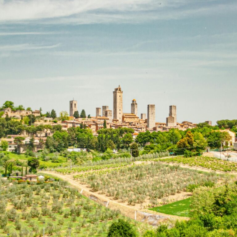 Aerial view of San Gimignano's medieval towers surrounded by lush Tuscan countryside.