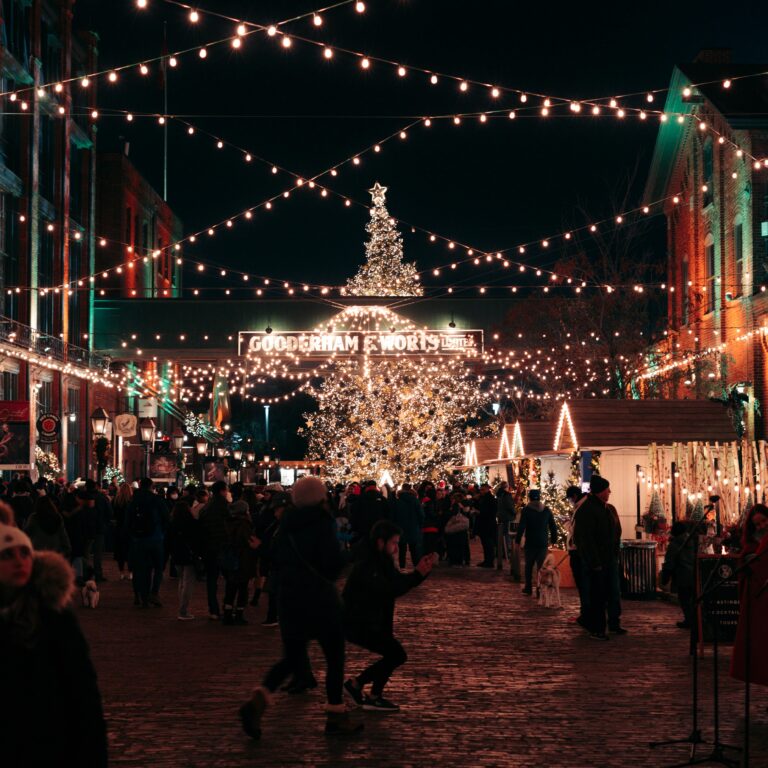 A vibrant Christmas market bustling with people under twinkling lights at night.